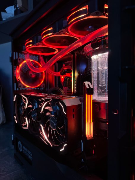 Ein beleuchteter Gaming-PC mit roten und orangefarbenen Lichtern und sichtbarem Kühlsystem.