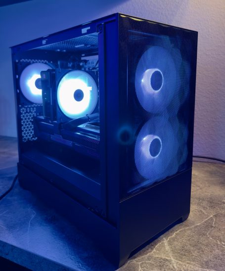Schwarzer Gaming-PC mit blauen Lüftern und transparentem Gehäuse.