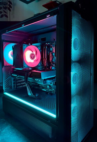 Ein beleuchteter Gaming-PC mit bunten Lüftern in einem dunklen Raum.